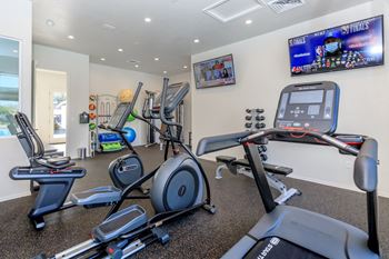 A gym with a row of treadmills and elliptical machines.